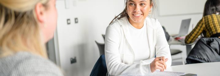 Students sitting at a desk chatting.